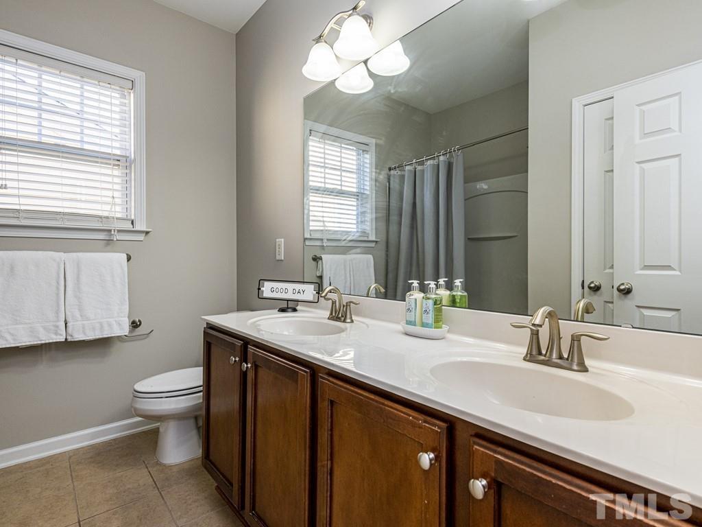 1136 Chapanoke Road Raleigh, NC 27603 - Photo 21 of 30 a bathroom with a granite countertop sink a toilet and a mirror