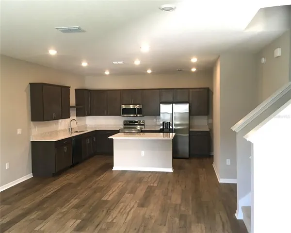 a kitchen with kitchen island granite countertop a sink a counter top space stainless steel appliances and cabinets