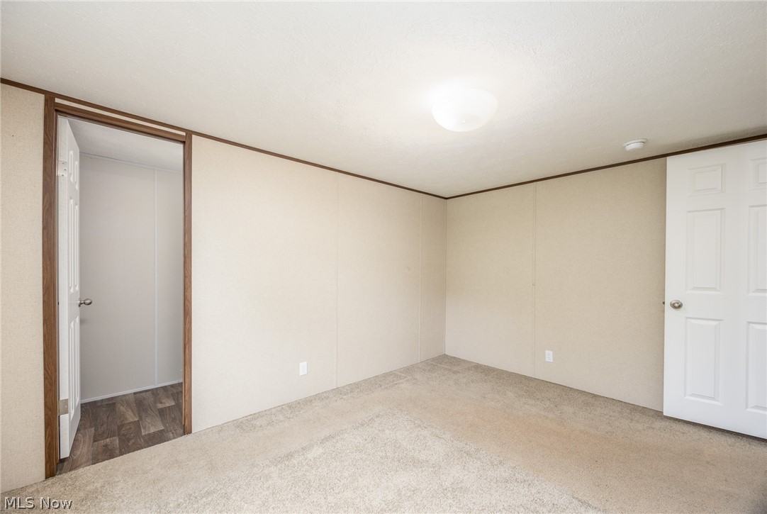 7455 Stanleyville Road Whipple, OH 45788 - Photo 25 of 37 Carpeted room featuring a white interior door, a doorway with wood-finish trim, and a ceiling-mounted light fixture