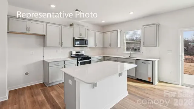 a kitchen with kitchen island a sink a stove a refrigerator cabinets and a window