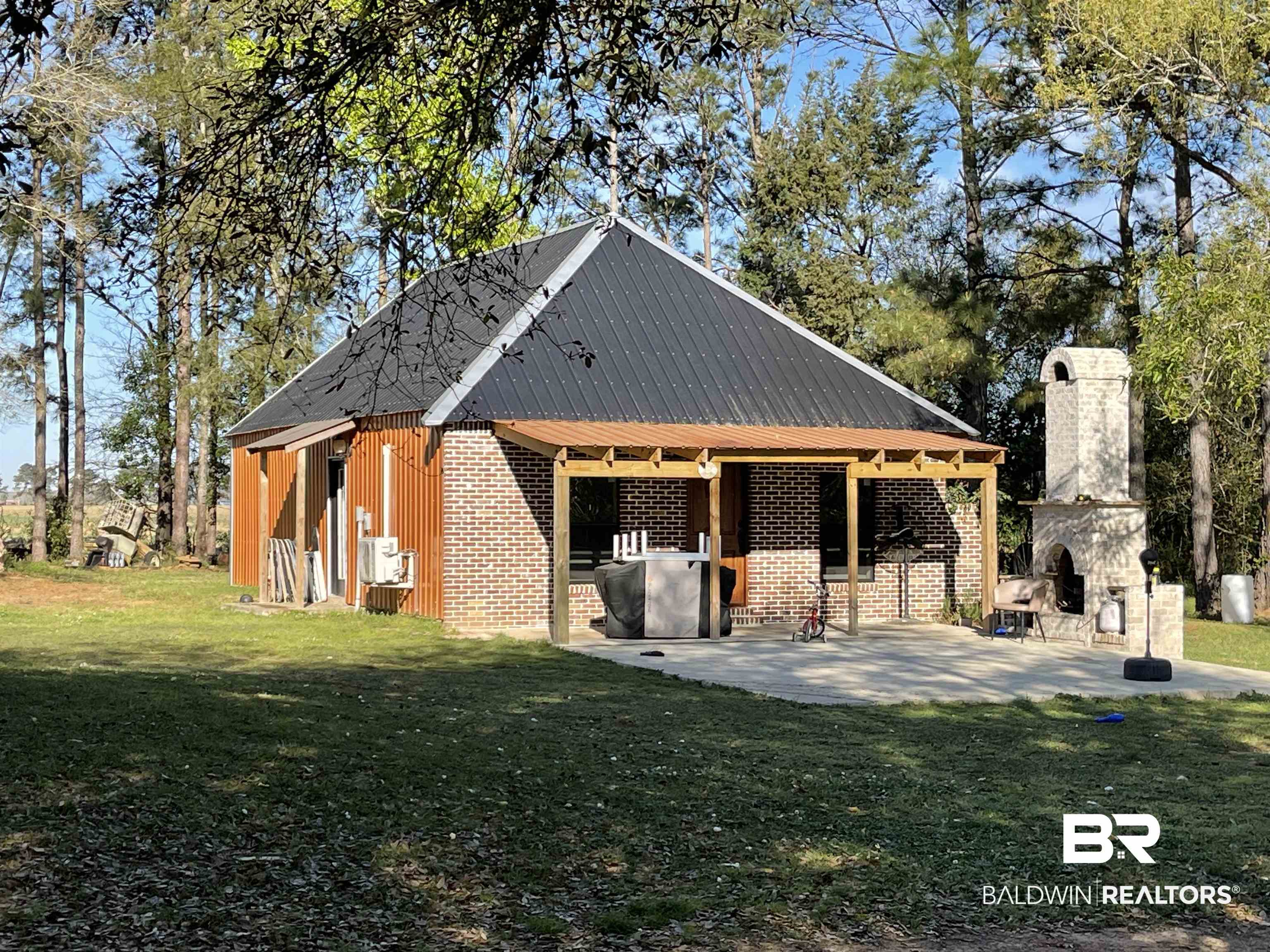 21593 Hubbard Road Robertsdale, AL 36567 - Photo 14 of 22 Exterior space featuring a yard, a patio area, brick siding, and an outdoor stone fireplace