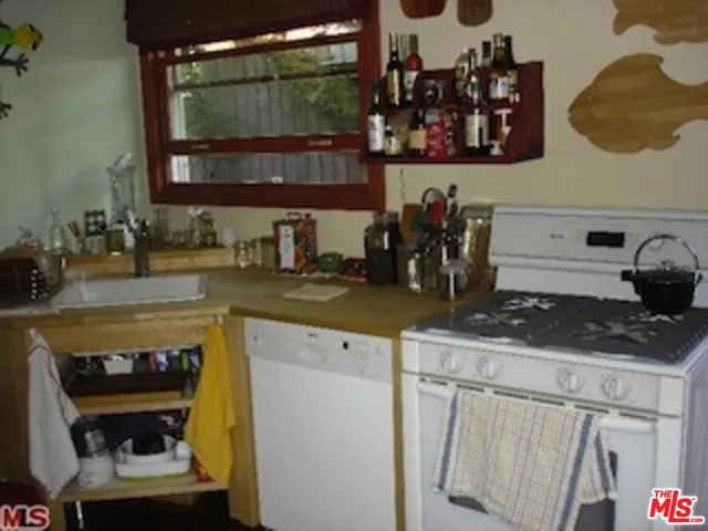 a kitchen with a sink and a stove with wooden floor