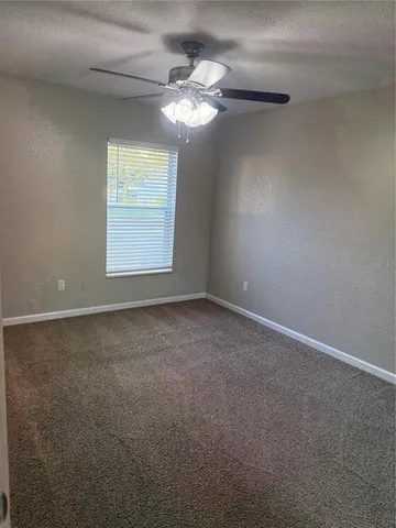 an empty room with a chandelier fan and windows