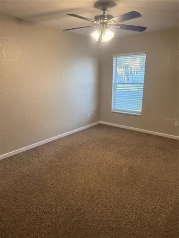 an empty room with windows and fan