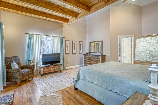 a bedroom with a bed wooden floor and a television