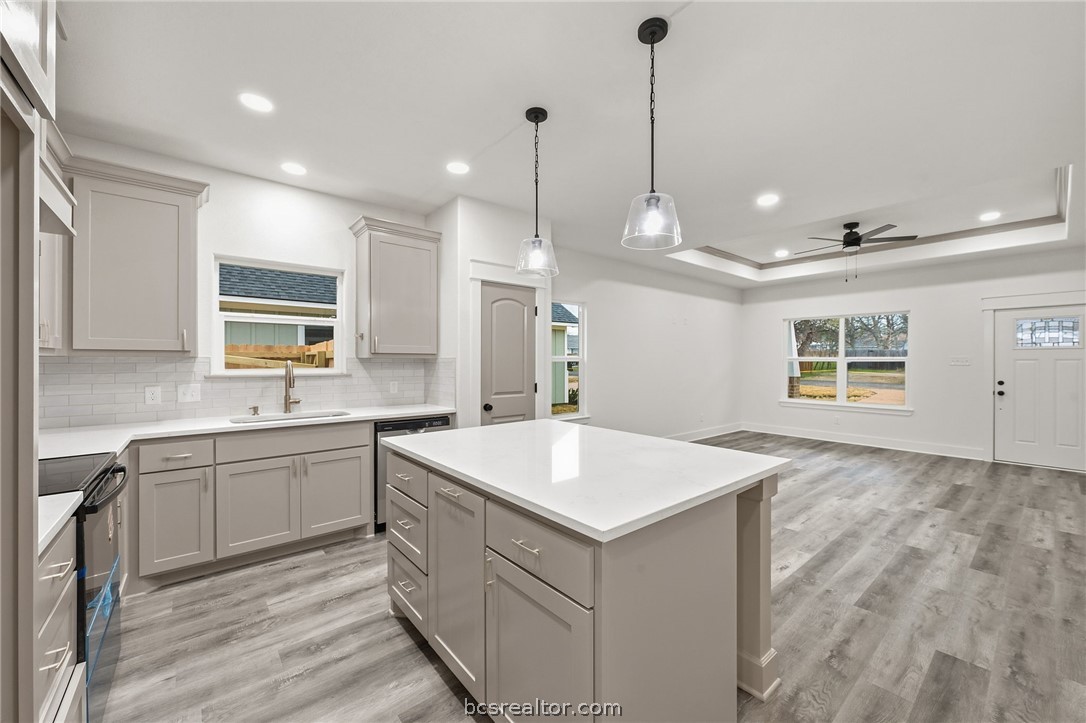 205 Lock Lane Bryan, TX 77803 - Photo 4 of 23 a large kitchen with kitchen island a sink a center island a stove a chimney and a window