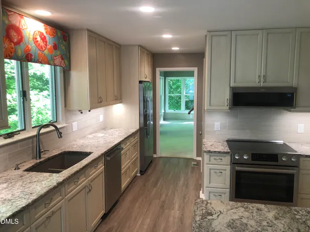 a kitchen with granite countertop a sink a counter space appliances and cabinets
