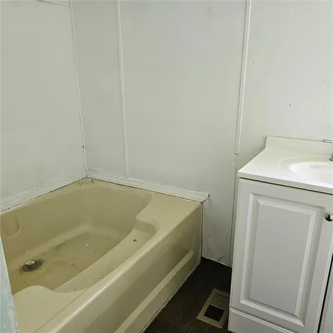 a bath tub sitting next to a white sink and vanity