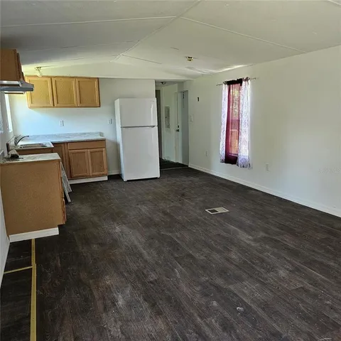 a view of a kitchen with a fridge and wooden floors