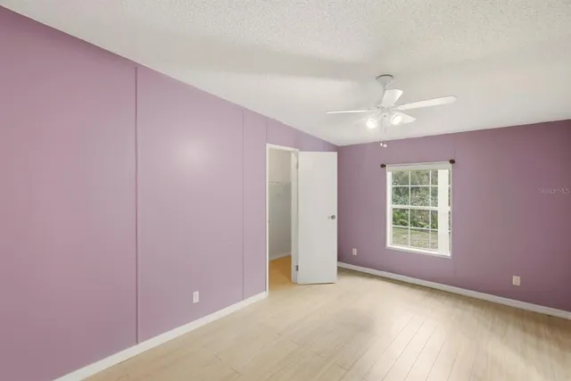 an empty room with closet and a ceiling fan