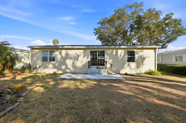 a view of house with patio outdoor seating and covered with trees