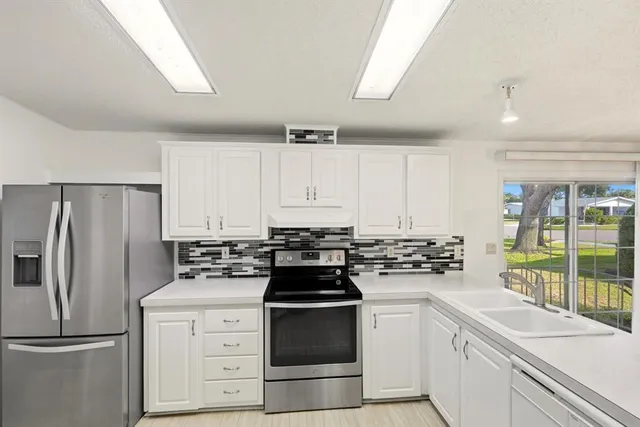 a large white kitchen with sink and cabinets