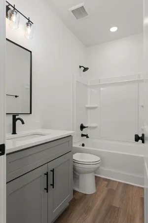 a bathroom with a sink a toilet a mirror and shower