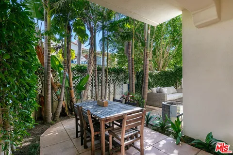 a view of a patio with table and chairs potted plants and large tree