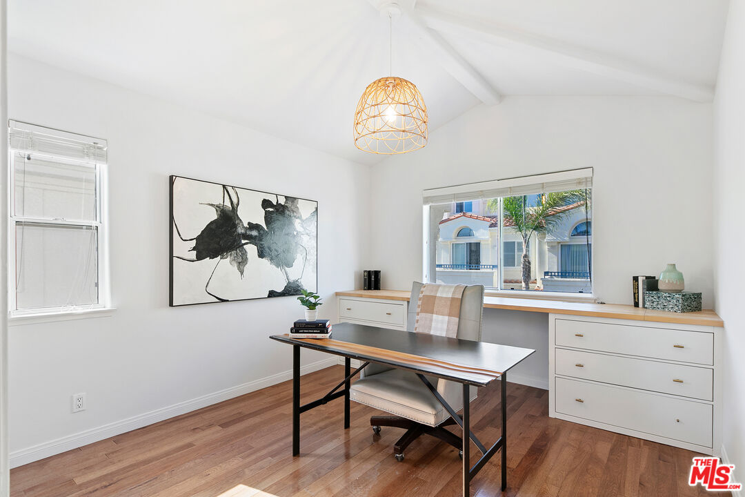 6477 Zuma View Place, Unit 125 Malibu, CA 90265 - Photo 24 of 33 a dining room with wooden floor a chandelier a wooden table and chairs