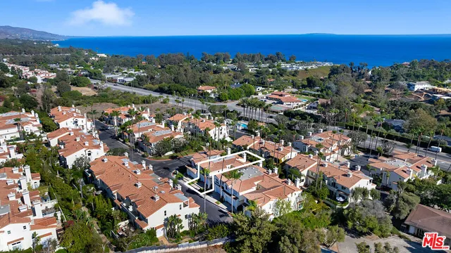 an aerial view of residential houses with outdoor space and trees