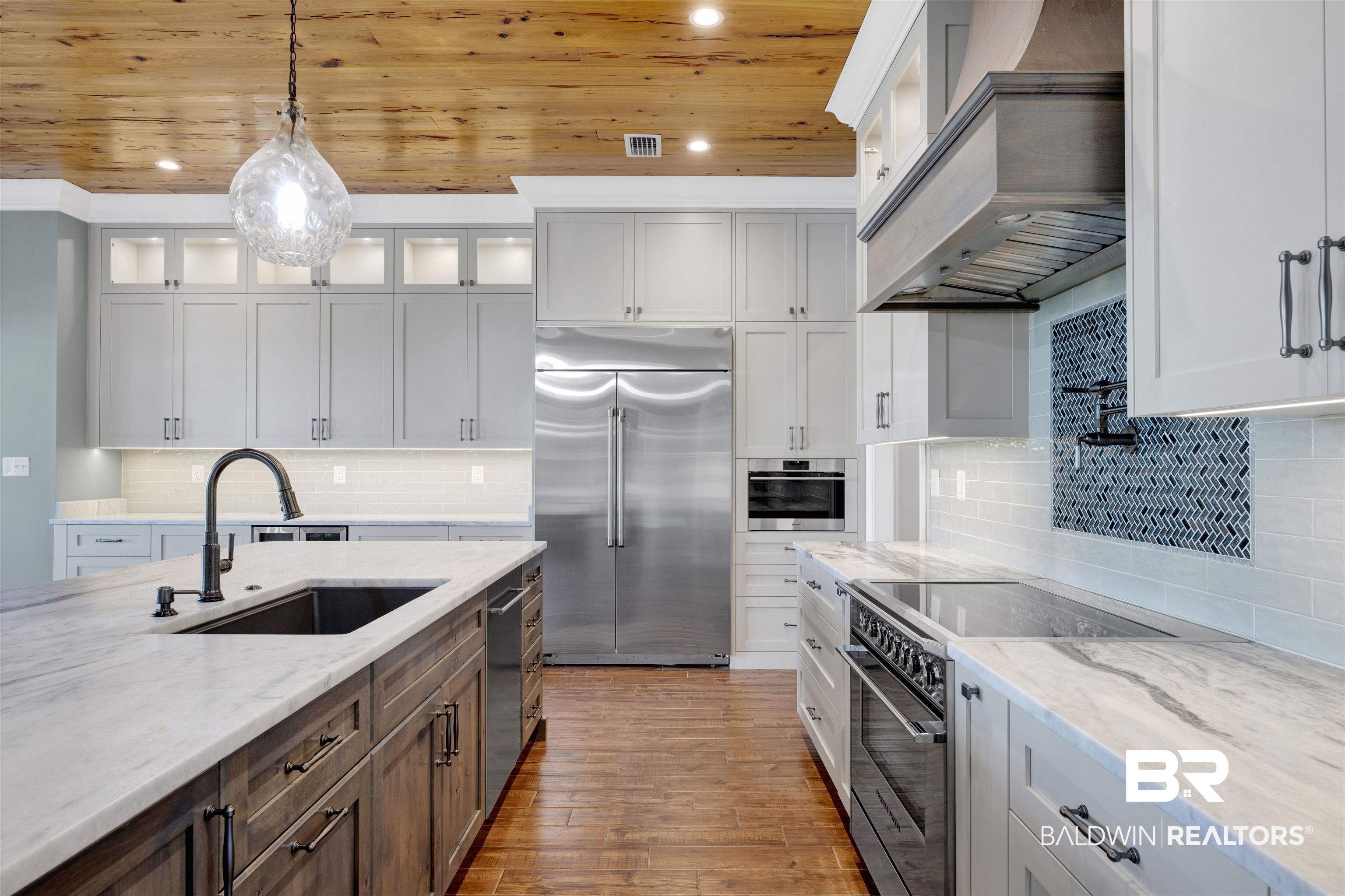 31729 River Road Orange Beach, AL 36561 - Photo 16 of 54 Kitchen featuring light stone countertops, stainless steel appliances, two tone cabinetry, light wood-type flooring, and hanging light fixtures