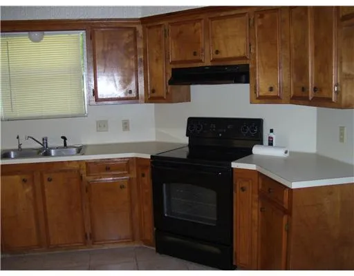a kitchen with granite countertop a refrigerator a stove a sink and dishwasher with wooden cabinets