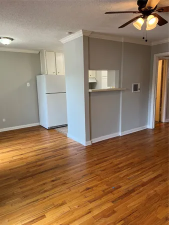 an empty room with wooden floor cabinet and windows