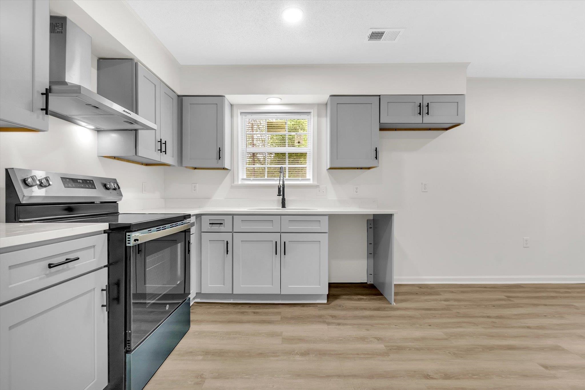 129 Tatlock Circle Covington, TN 38019 - Photo 5 of 16 Kitchen featuring stainless steel range with electric stovetop, light wood-style flooring, gray cabinetry, and recessed lighting