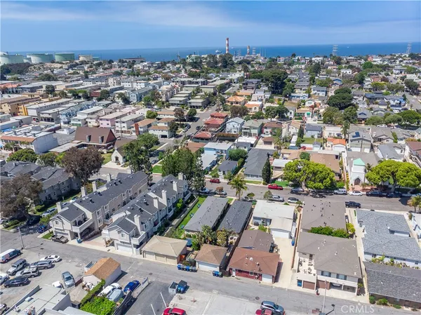 an aerial view of a city with lots of residential buildings and ocean view in back