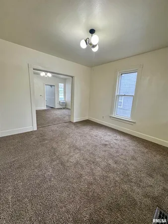 a view of an empty room with a chandelier fan