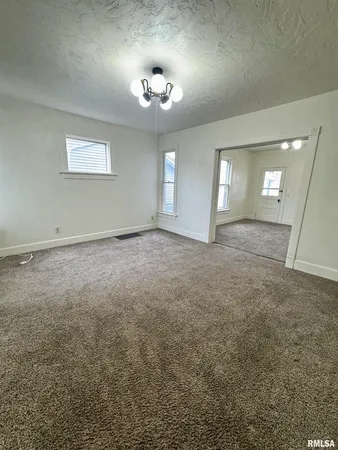 an empty room with a chandelier fan and windows