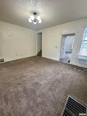 an empty room with a chandelier fan and windows