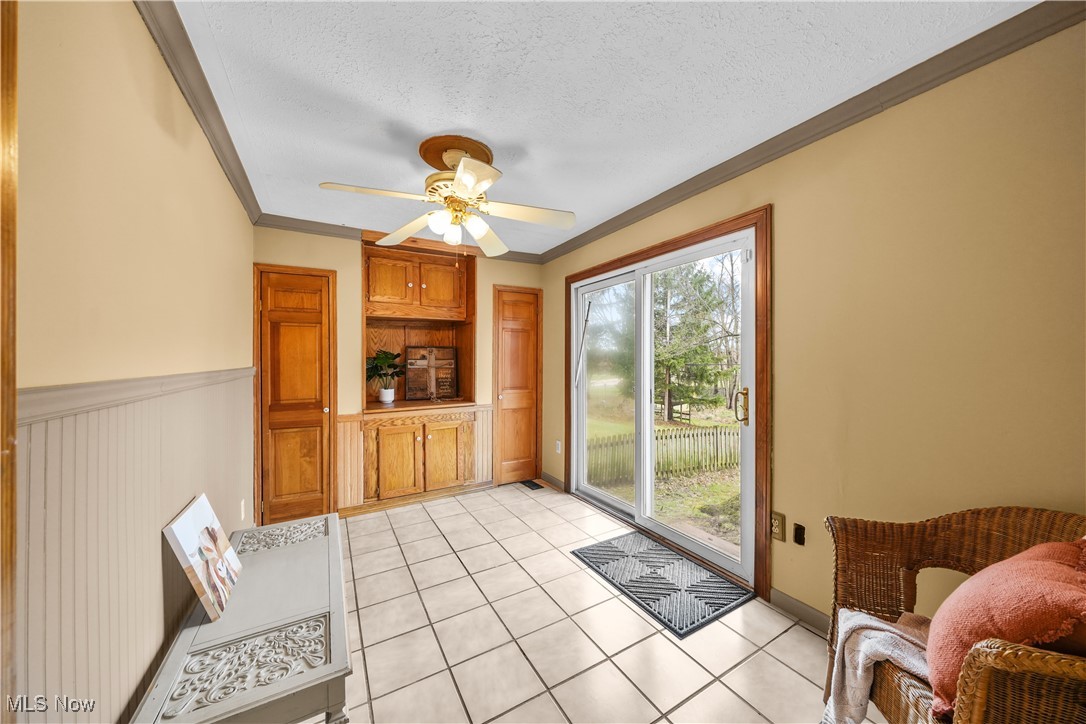 4819 Westbourne Road Cleveland, OH 44124 - Photo 18 of 39 Entryway featuring light tile patterned flooring, a wainscoted wall, a textured ceiling, ceiling fan, and ornamental molding