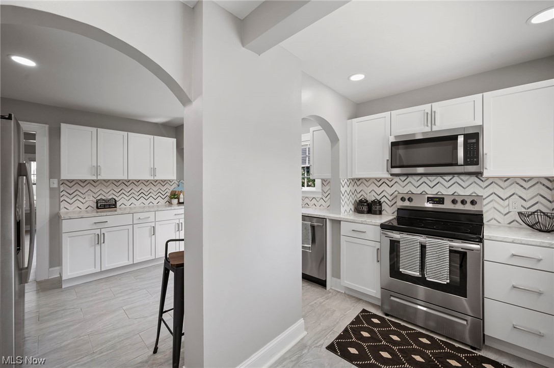 1022 Englewood Road Cleveland, OH 44121 - Photo 13 of 33 Kitchen with backsplash, appliances with stainless steel finishes, and white cabinets