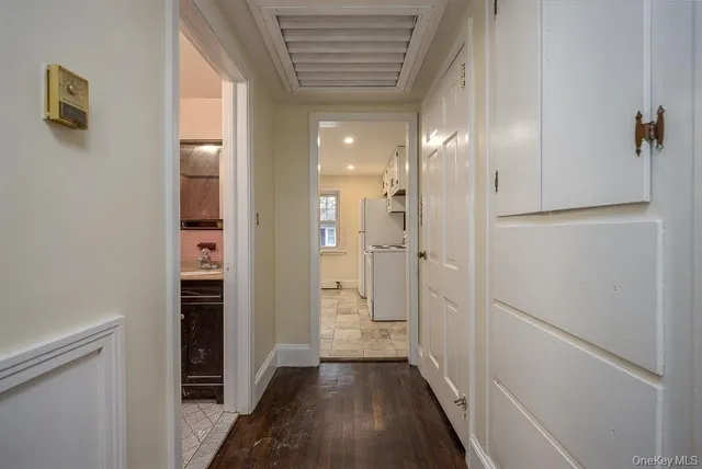 a view of a hallway with wooden floor and a refrigerator