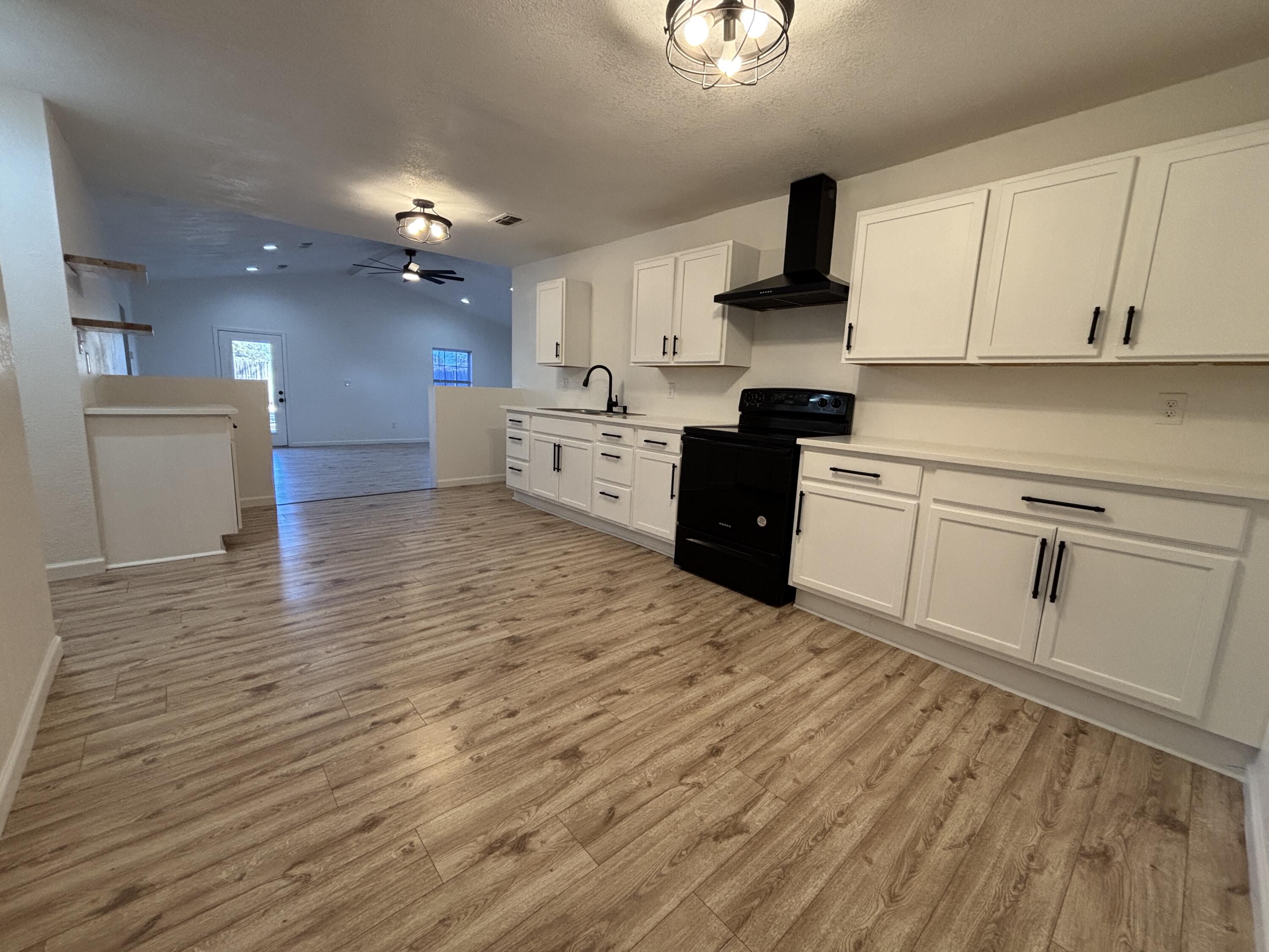 2718 Cornell Street Lubbock, TX 79415 - Photo 6 of 13 a kitchen with granite countertop a stove top oven a sink dishwasher and a refrigerator with wooden floor