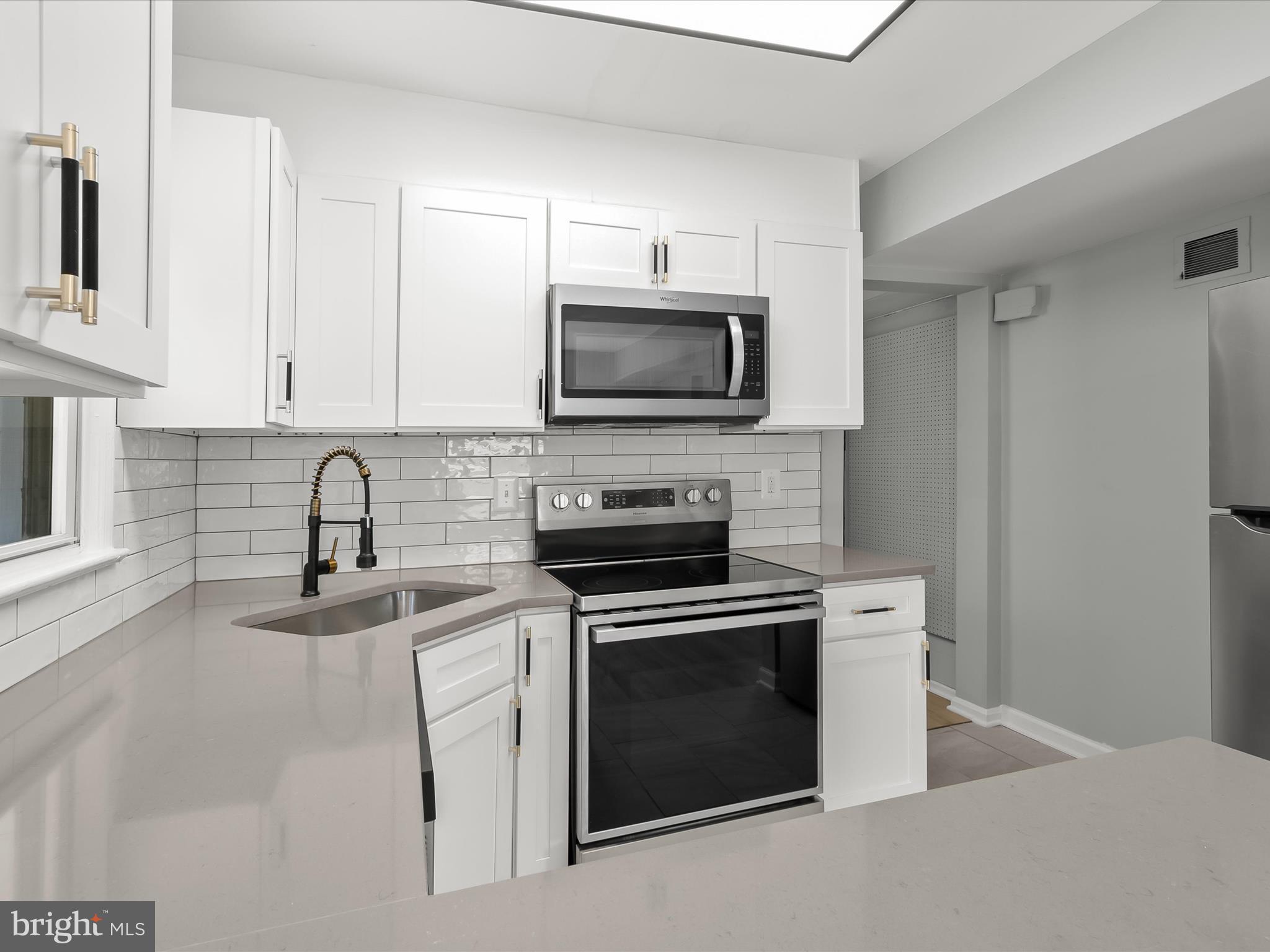 6806 10th Avenue Takoma Park, MD 20912 - Photo 17 of 39 a kitchen with granite countertop a stove top oven microwave and sink
