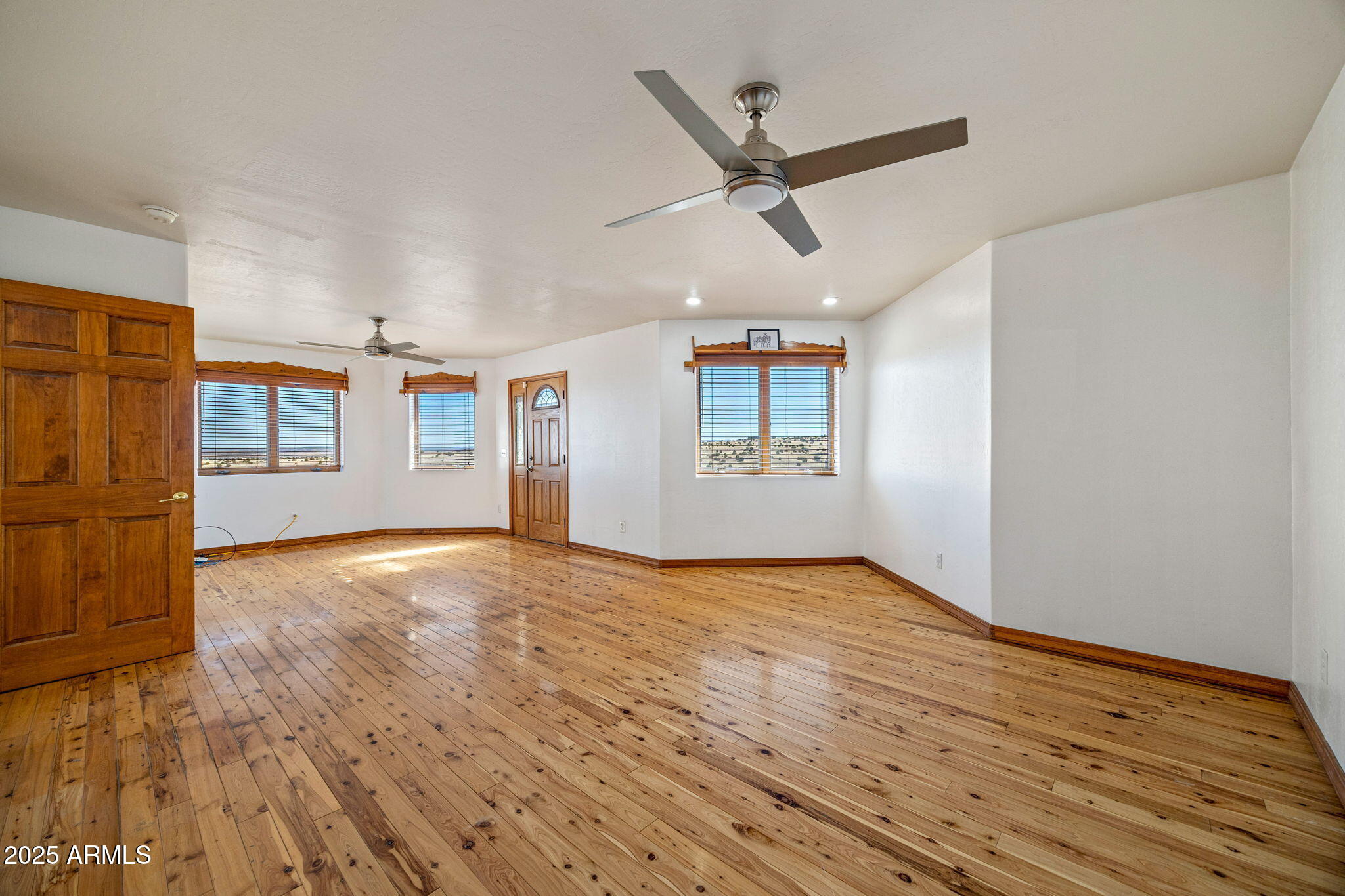 800 Arena Estates Taylor, AZ 85939 - Photo 21 of 50 an empty room with wooden floor ceiling fan and windows