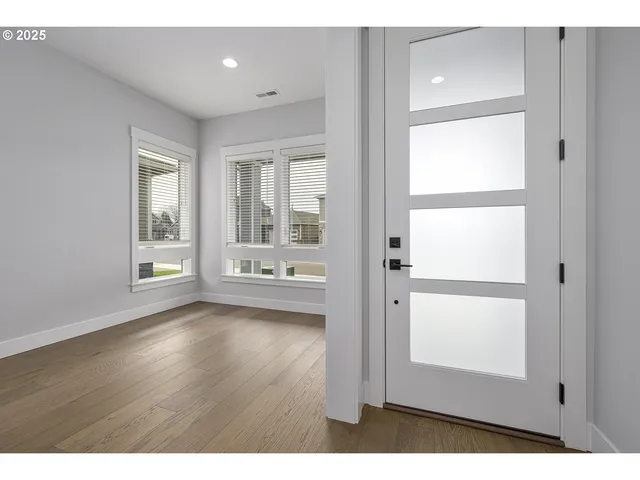 a view of an empty room with a window and wooden floor