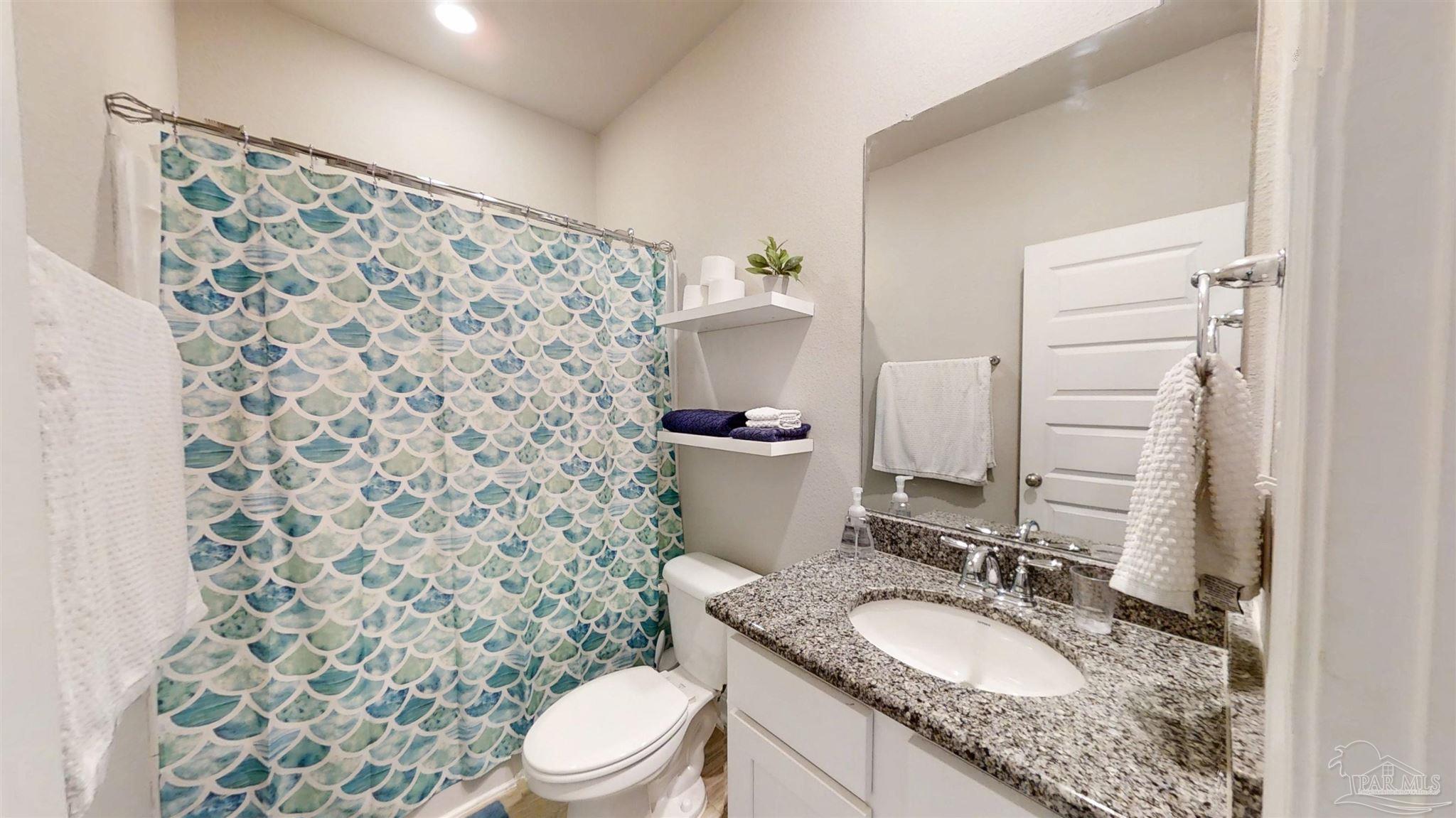 421 Apollo Avenue Gulf Shores, AL 36542 - Photo 42 of 72 a bathroom with a granite countertop toilet sink and mirror
