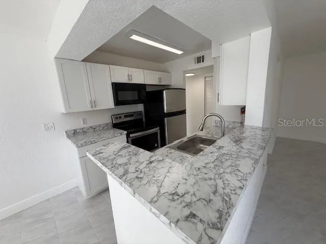 a kitchen with stainless steel appliances granite countertop a sink refrigerator and microwave