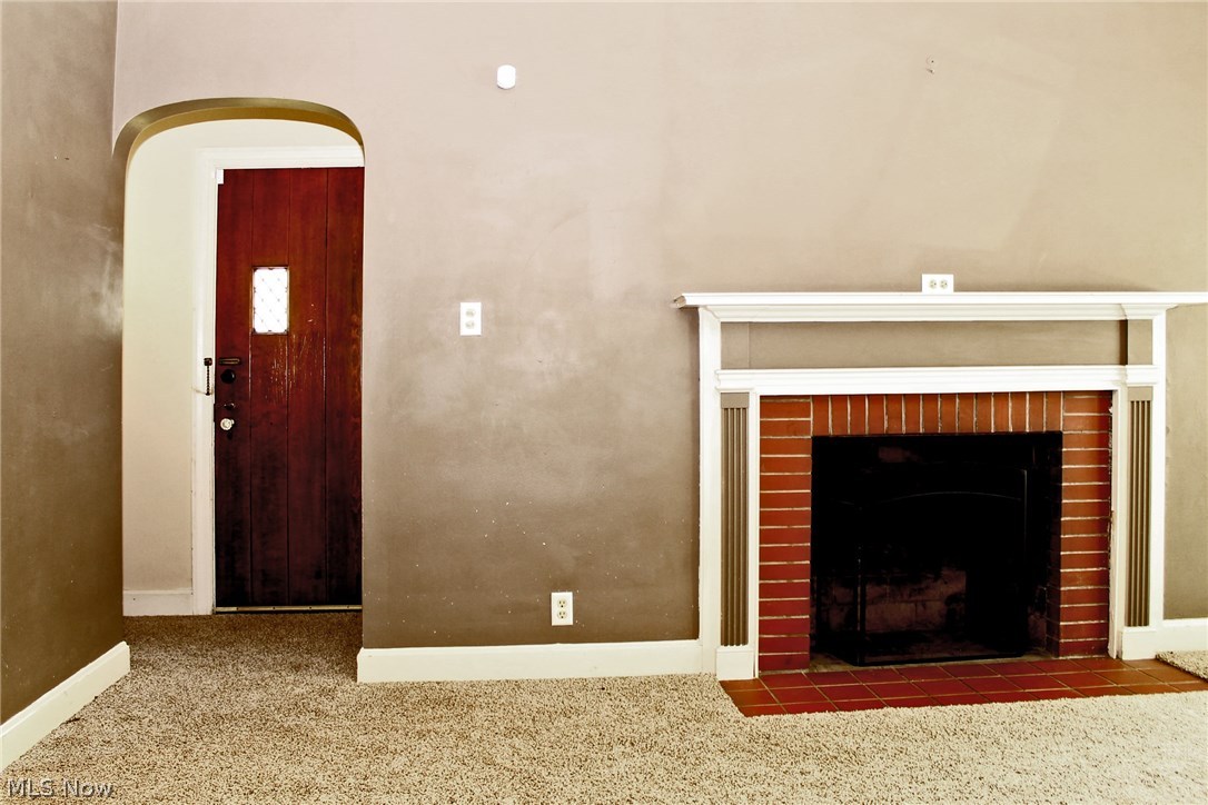 Leaded glass hardwood entry door to living room with mantled fireplace.