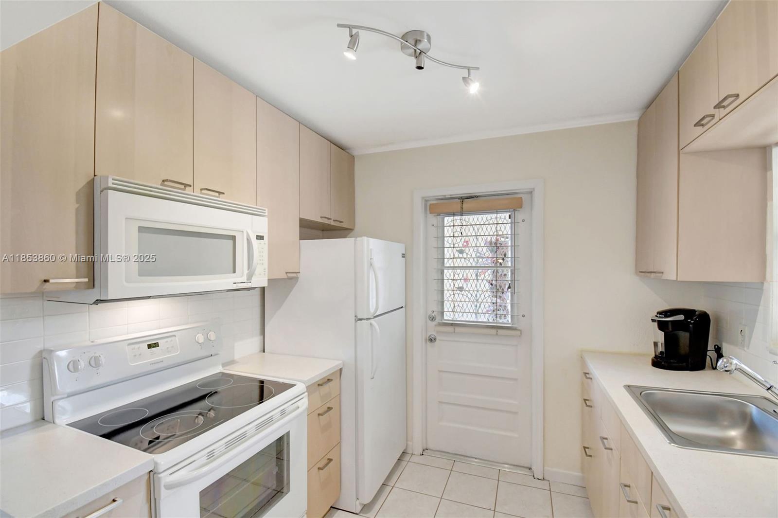 415 Northeast 2nd Street, Unit 124 Hallandale Beach, FL 33009 - Photo 19 of 36 a kitchen with white cabinets and white appliances