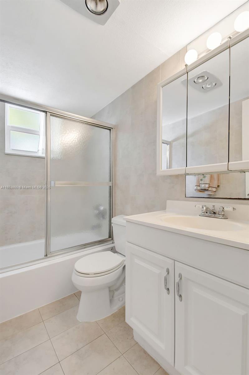 415 Northeast 2nd Street, Unit 124 Hallandale Beach, FL 33009 - Photo 32 of 36 a bathroom with a granite countertop sink a toilet a mirror and shower