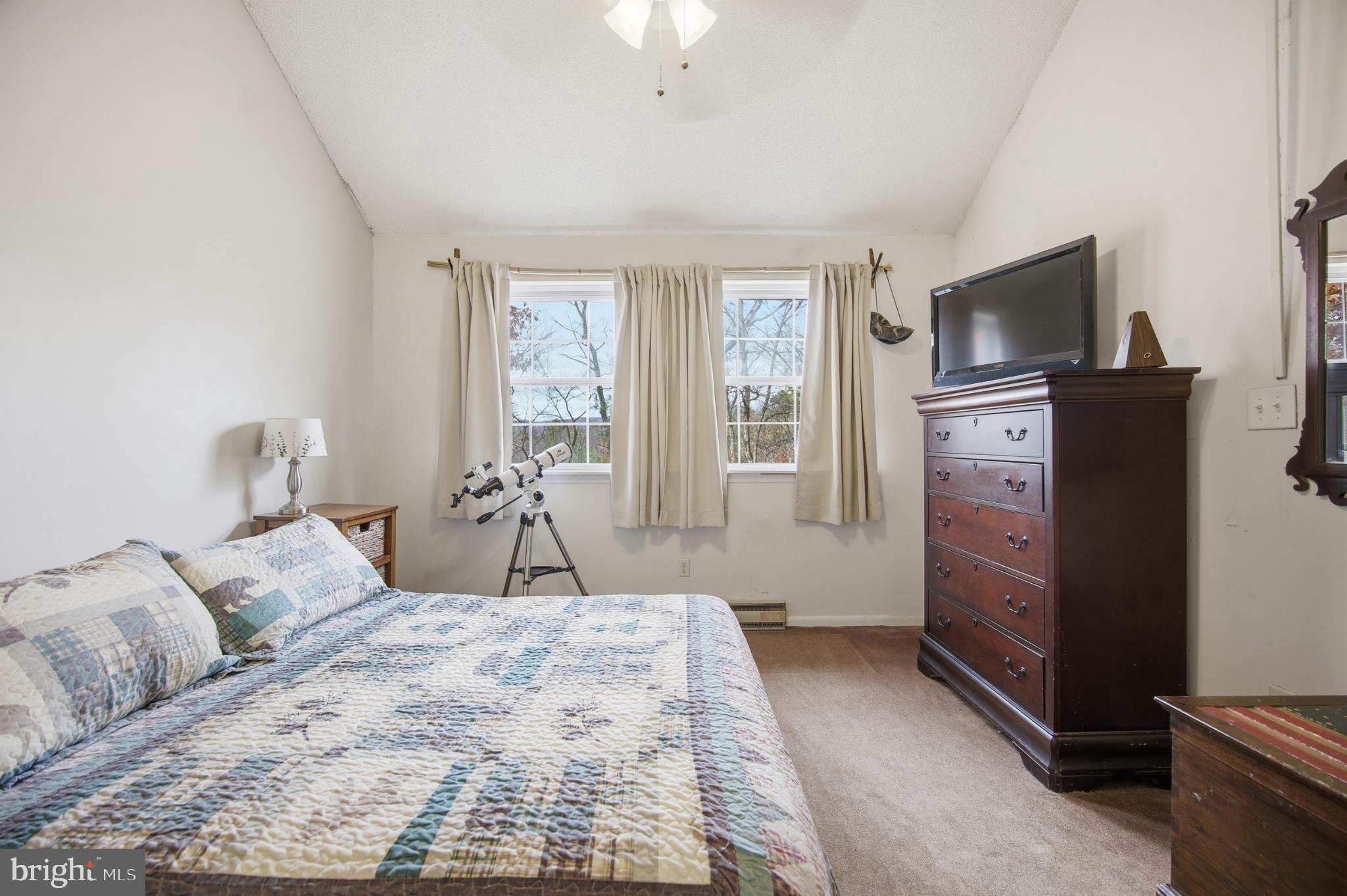 128 Hemlock Lane Gerrardstown, WV 25420 - Photo 7 of 44 a bedroom with a large bed and flat tv screen on a dresser