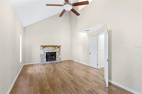 a view of an empty room with wooden floor fireplace and a window