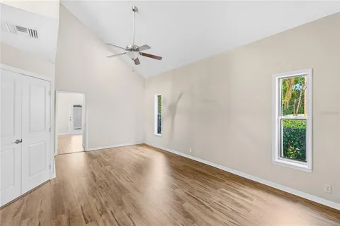 a view of empty room with wooden floor and fan