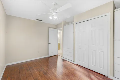 an empty room with wooden floor fan and windows