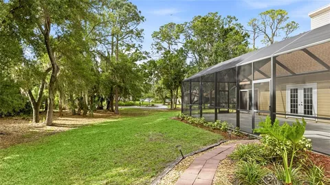 an aerial view of a house with a yard and trees all around