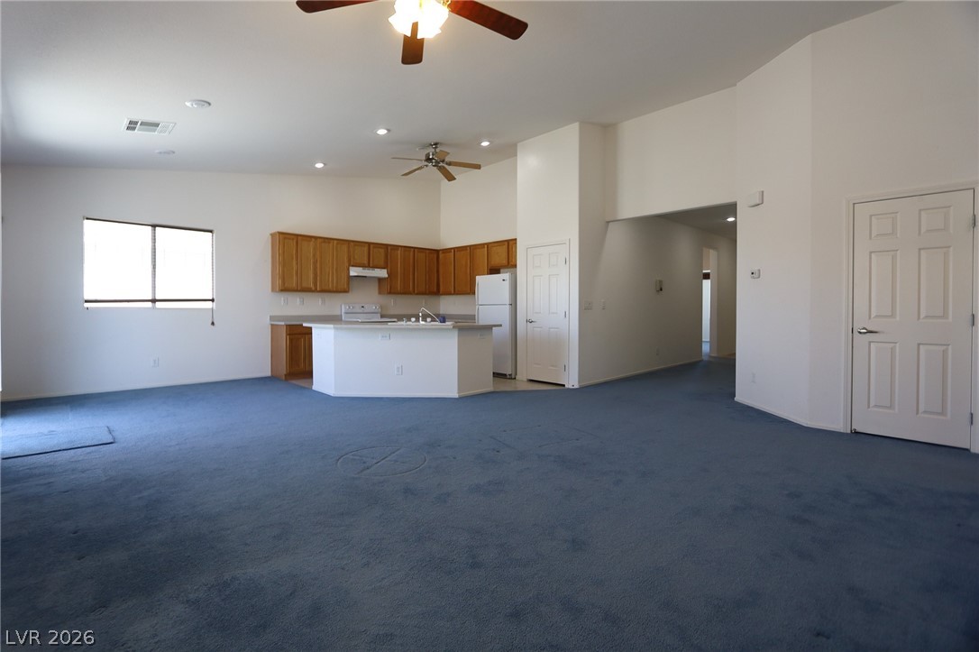 6472 Centennial Road Pahrump, NV 89048 - Photo 4 of 29 An open concept living area boasts a kitchen with light wood cabinetry and an integrated island, all illuminated by recessed lighting.