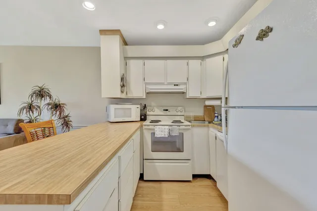 a kitchen with a sink a stove a refrigerator and white cabinets