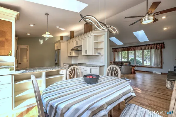 a kitchen with stainless steel appliances kitchen island granite countertop a table chairs in it and wooden floors