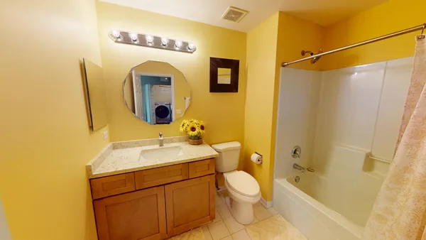 a bathroom with a toilet sink vanity tub and shower