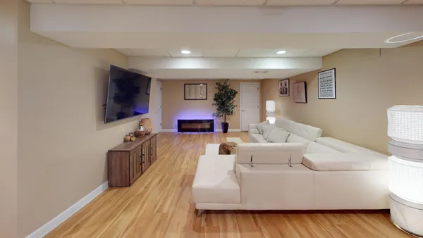 a living room with furniture a flat screen tv and a refrigerator